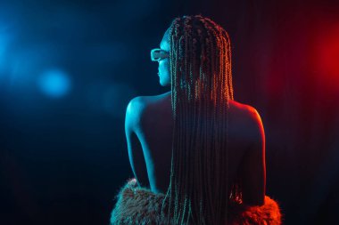 Siyah ırktan, mavi ve kırmızı renkli örgülü bir kadın. Sırtında model olan bir portre.