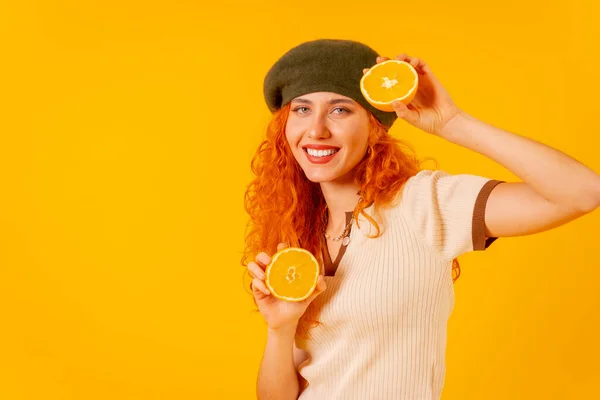 Червоноголові Жінка Тримає Апельсин Над Ізольованим Жовтим Фоном Посміхаючись Фруктом — стокове фото