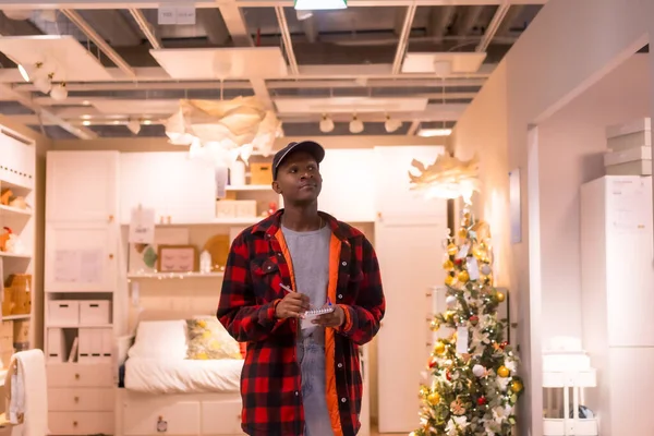 stock image Black ethnic man shopping in a supermarket for almeadas and cushions. christmas shopping