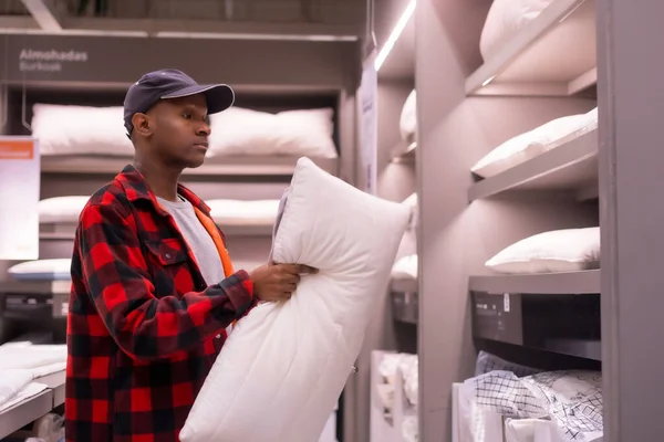 stock image Black ethnic man shopping in a supermarket for almeadas and cushions. Looking at the pillows