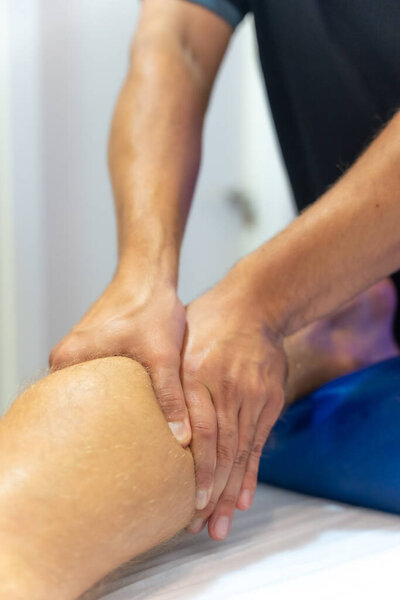 Физиотерапевт делает физиотерапевтический массаж клиенту на шаре ноги