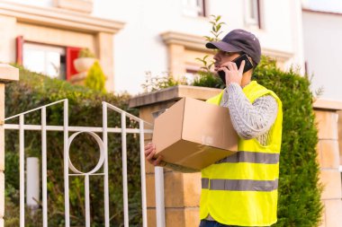 Çevrimiçi bir dükkandan paket teslimatçısı, elinde bir kutu ile