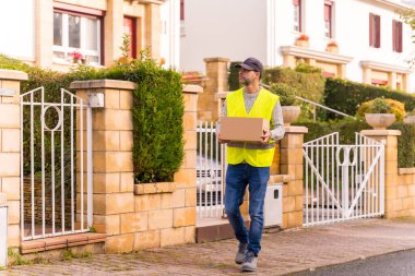 Online bir dükkandan paket teslimatçısı elinde bir kutuyla evi arıyor.