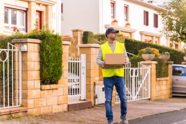 Online bir dükkandan paket teslimatçısı, elinde bir kutu ile bazı evlerde