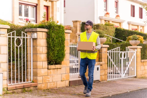 Stock image Package delivery driver from an online store, with a box in hand looking for the house