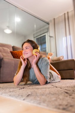 Beyaz kadın müzik dinliyor oturma odasında halı, kanepe, hayal, özgürlük