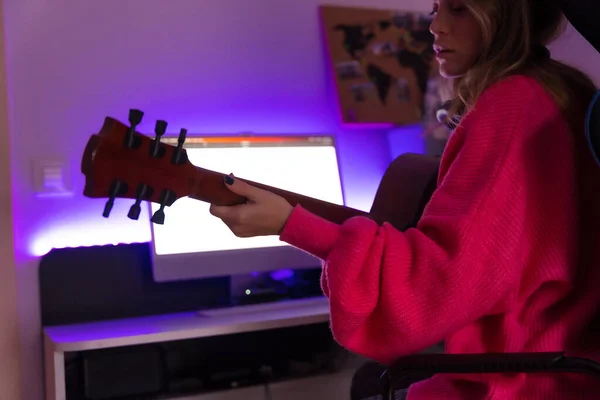 Woman learning to play the guitar with online classes on the computer