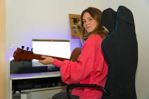 Portrait of caucasian woman learning to play guitar with online classes on computer