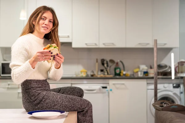 Vegetarian woman eating a vegetable sandwich in the kitchen at home. healthy nutrition