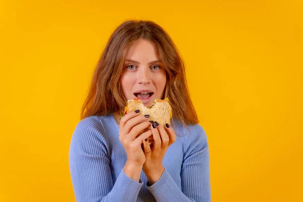 Vegetarian woman biting a sandwich on a yellow background, healthy vegetarian food