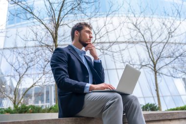 Toplantıya girmeden önce düşünen genç işadamı veya finans adamı, cam bina