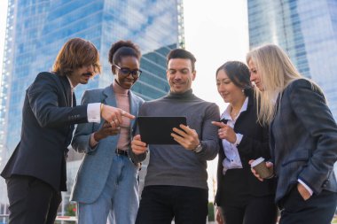 A group of multi-ethnic business people in a business park looking at a tablet
