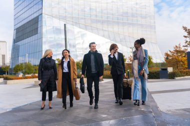 Group of multi-ethnic business people with suitcases in a business park walking to work
