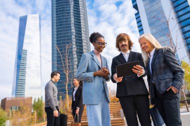 Multi-ethnic business colleagues or executives, looking at technologies, business park exterior