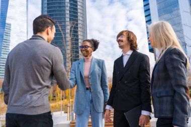 Group of multi-ethnic businessmen or executives, introducing each other greeting shaking hands in a business park