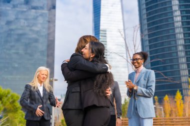 Middle-aged multiethnic businessmen and businesswomen, coworkers hugging, good work environment