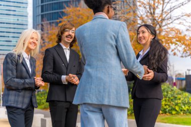Middle-aged multi-ethnic businessmen and businesswomen shaking hands in good working environment