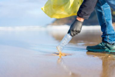 Unrecognizable person collecting garbage or plastic on the beach. ecology concept