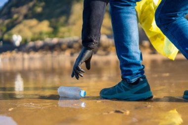 Sea pollution, unrecognizable person walking on the beach collecting plastics. ecology concept