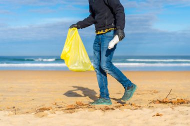 Sea pollution, unrecognizable person collecting plastics in the sand on the beach. ecology concept