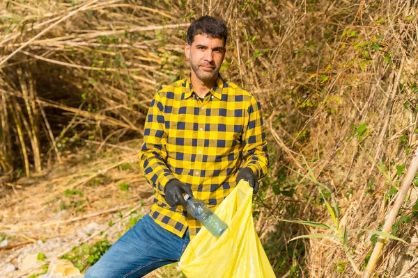 Portrait of man collecting garbage in a forest. Ecology, clean nature from plastics