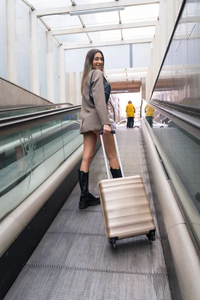 Tourist woman with suitcase in the city on an escalator going up from the subway, vacation concept