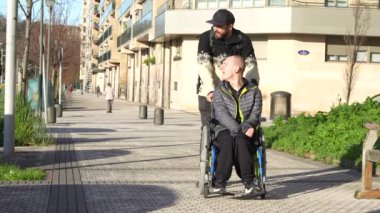 Disabled person walking having fun with friend in wheelchair on the street