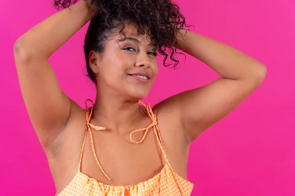 Portrait of a curly-haired woman in summer clothes on a pink background, studio shot