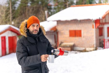 Man drinking coffee from a hot thermos in winter in the snow