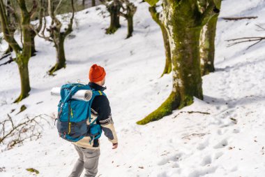 Hiker with backpack on his back walking on a trekking on the snow, winter adventures, nature activity