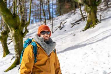 Portrait of a hiker with a backpack on a snow trekking, winter adventures in a beech forest