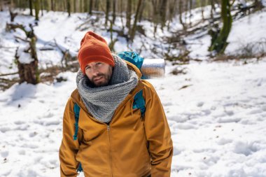 Portrait of a hiker with a backpack on a snow trekking, winter adventures in a beech forest