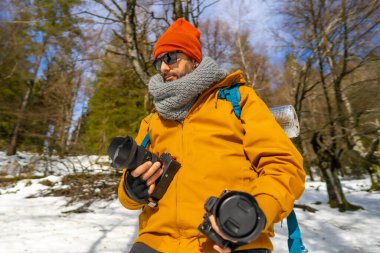 Portrait of a photographer trekking with backpack with two cameras in hand winter hobby