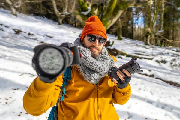 Portrait of a photographer trekking with backpack with two cameras in hand winter hobby