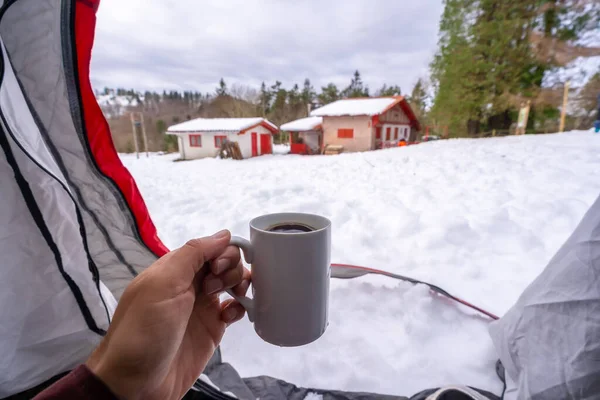 Having a coffee in a cup inside a tent on a winter morning, winter free camping