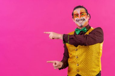 Clown with white facial makeup showing an empty space from the pink background, announcing something
