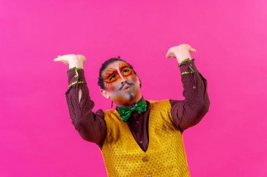 Clown with white face makeup showing empty space on pink background, announcing something, pointing up