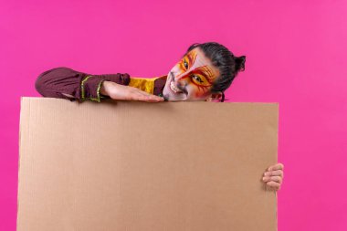 Clown with white facial makeup showing a sign on a pink background, announcing something