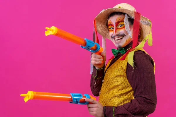 ピンクの背景に白い顔のメイクとクラウン おもちゃの銃と帽子で笑顔 — ストック写真