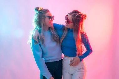 Diskoda dans eden, gülümseyen ve kucaklayan iki genç sarışın beyaz kadın.