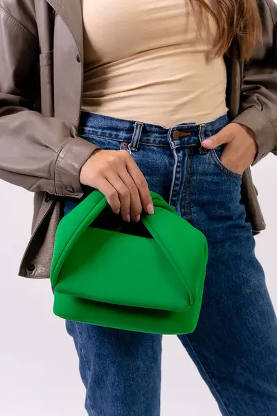Hand of a woman with a green handbag on a white background, fashion studio
