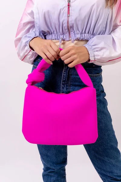 Hand of a woman with a pink bag on a white background, fashion studio