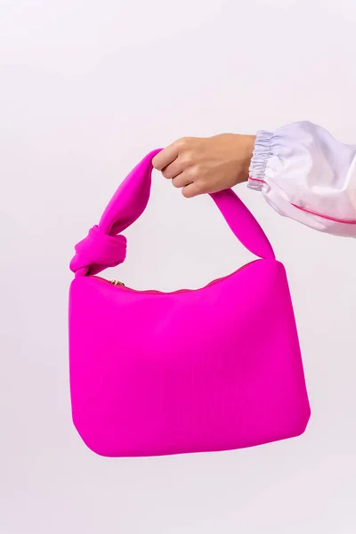 Hand of a woman with a pink bag on a white background, fashion studio