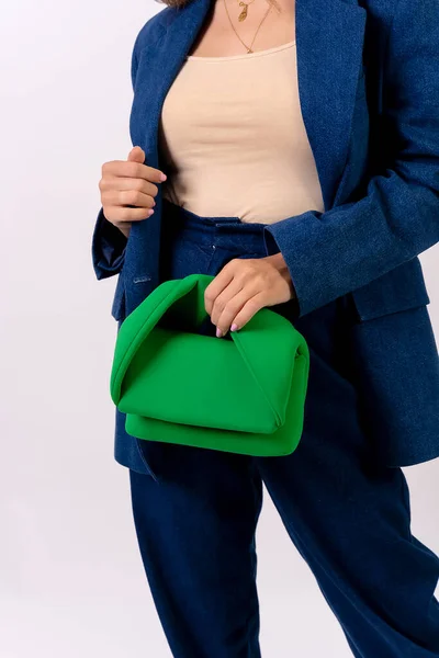 Hand of a businesswoman with a green bag on a white background, fashion studio