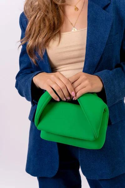 Hand of a businesswoman with a green bag on a white background, fashion studio