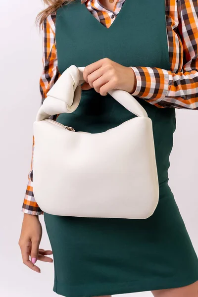 Hand of a businesswoman with a cream handbag on a white background, fashion studio