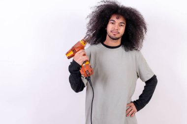 Portrait of the carpenter technician with the drill. Young boy with afro hair on white background