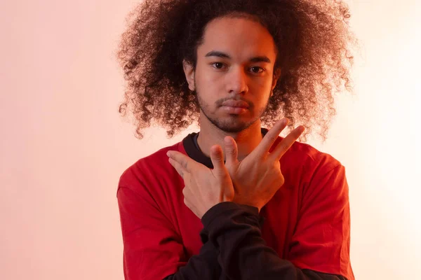 Portrait with a red led light with a rapper gesture. Young man with afro hair on white background