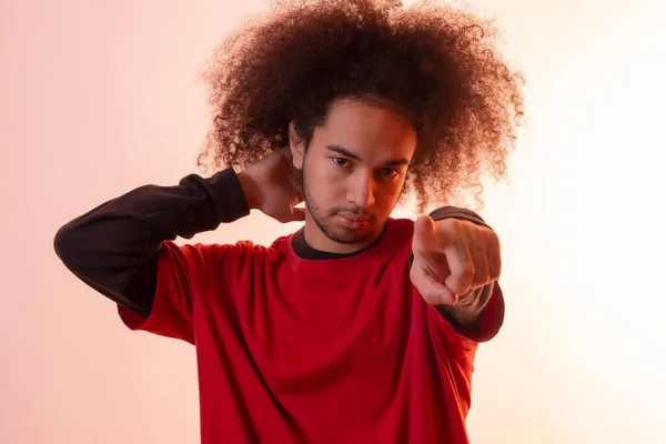 Portrait with a red led light pointing. Young man with afro hair on white background