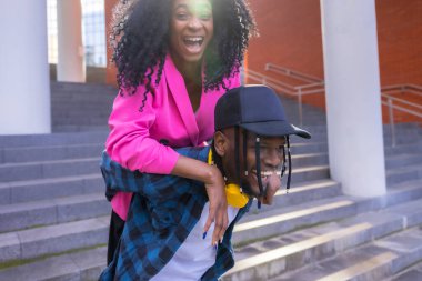 Young african american women in the city, lifestyle of friends, riding on top of the guy having fun